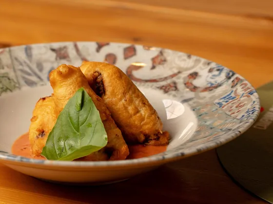 Il fritto appena uscito, dorato, appoggiato su una crema di pomodoro