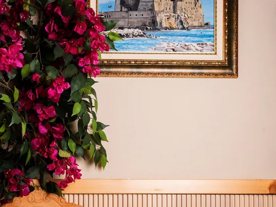 Un angolo del locale: una stampa incorniciata di un castello sul mare e una cascata di bouganville
